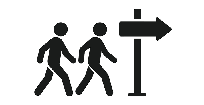 Two people walking towards directional sign