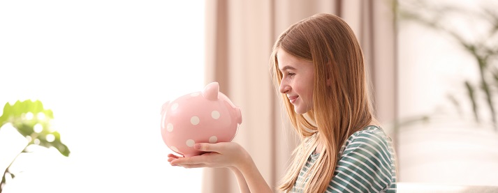 Teen girl with piggy bank at home