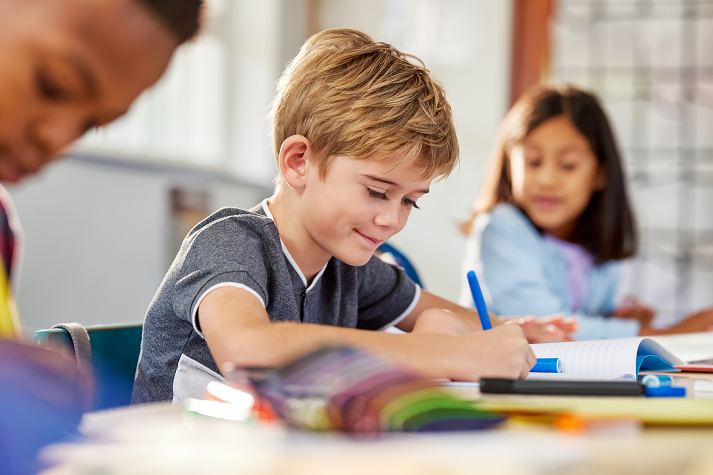 Elementary school boy writing on a notebook at school