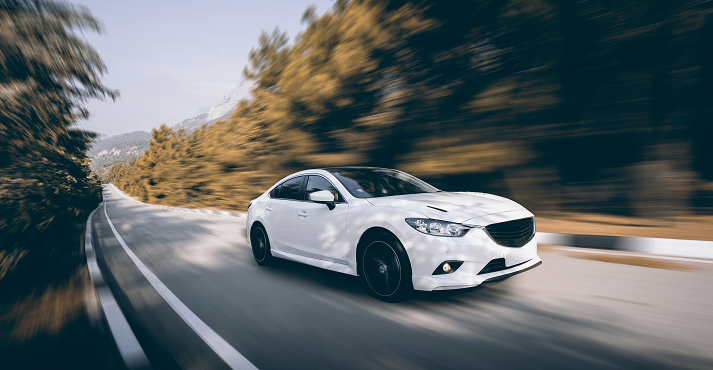 White car speed driving on asphalt road at daytime