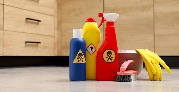 Bottles of toxic household chemicals Bottles of toxic household chemicals with warning signs, gloves and brush on floor indoors