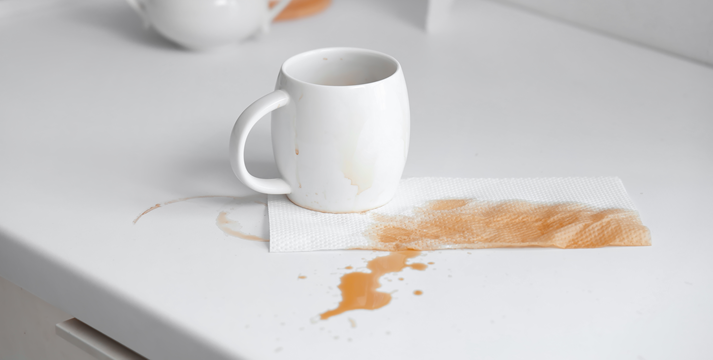 Cup and paper towel with coffee stains on table in kitchen