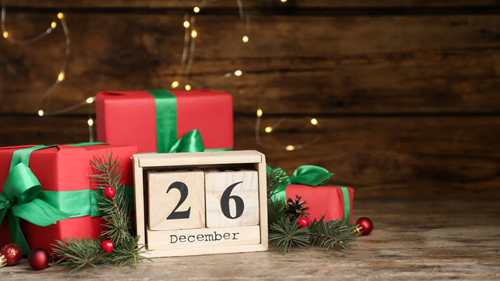 Block calendar with Boxing Day date near gifts on wooden table