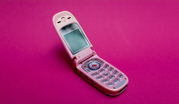 Cool and classic pink retro flip cell or mobile phone isolated against a red background
