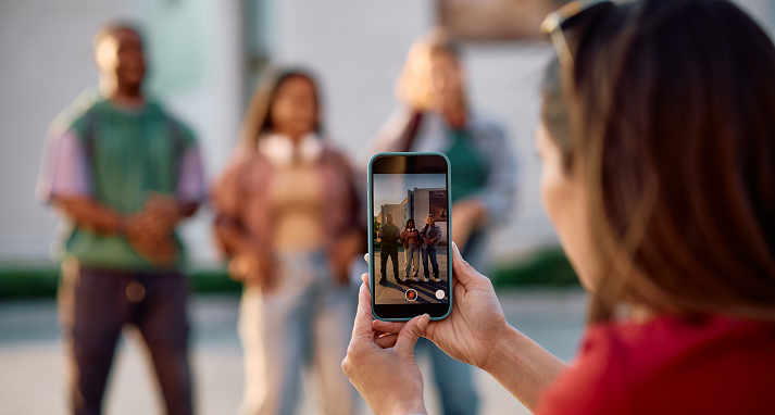Close up of student filming her friends with smart phone at university campus.