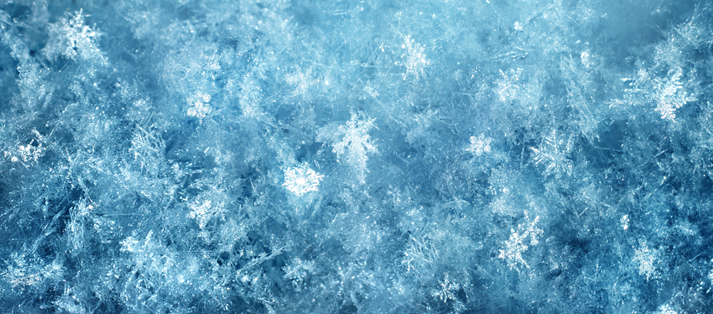 Macro photography of delicate ice and hoarfrost crystals forming natural snowflake patterns on a deep blue winter background