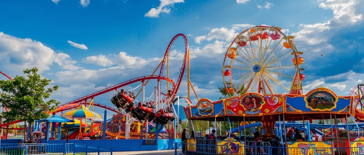 amusement park A vibrant amusement park scene featuring colorful roller coasters and a Ferris wheel under a blue sky with visitors enjoying various attractions