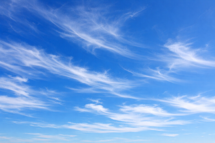 A deep blue sky with thin, white, wispy cirrus clouds stretched across it